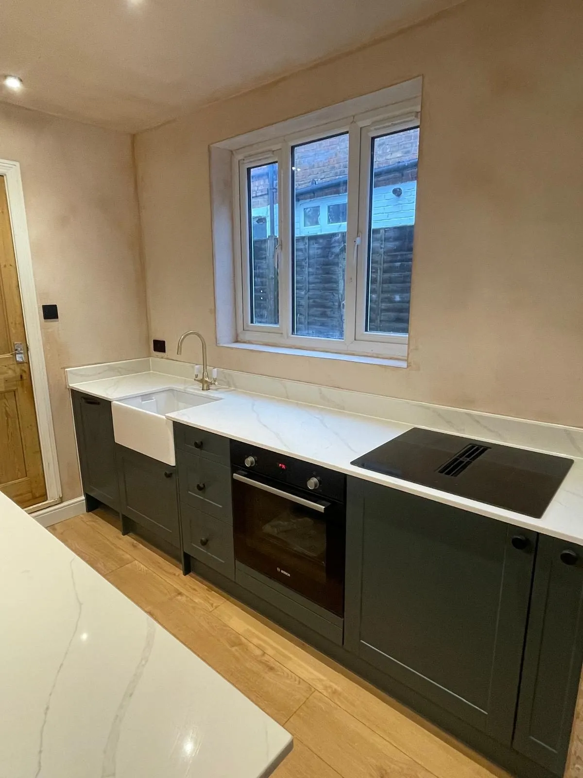 Renovated kitchen with dark cabinets and white worktops in Egham